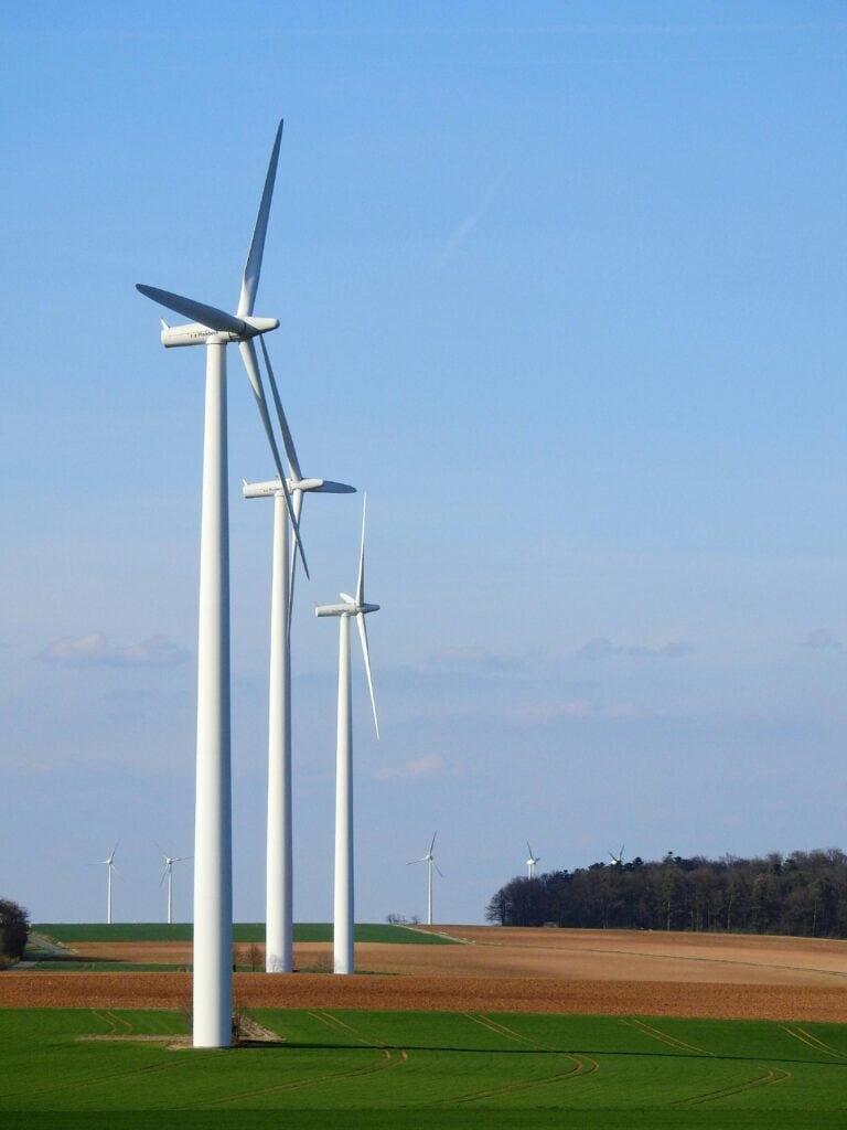 Row of wind turbines in a rural area, generating renewable energy under a blue sky.